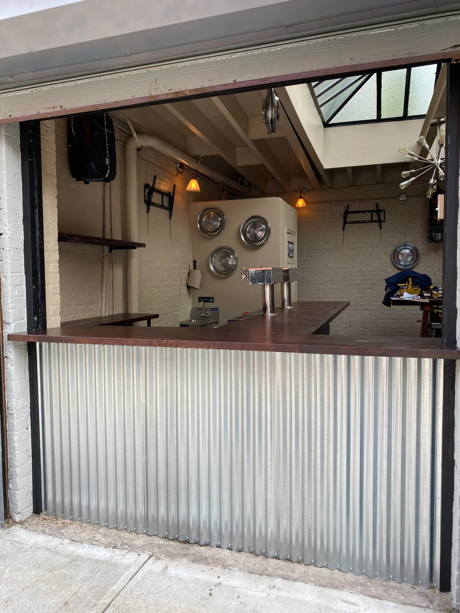 The bar counter at The Beer Garage, 148 5th Avenue, seen through the open garage door, for a guide to the best bar snacks and wings in Park Slope