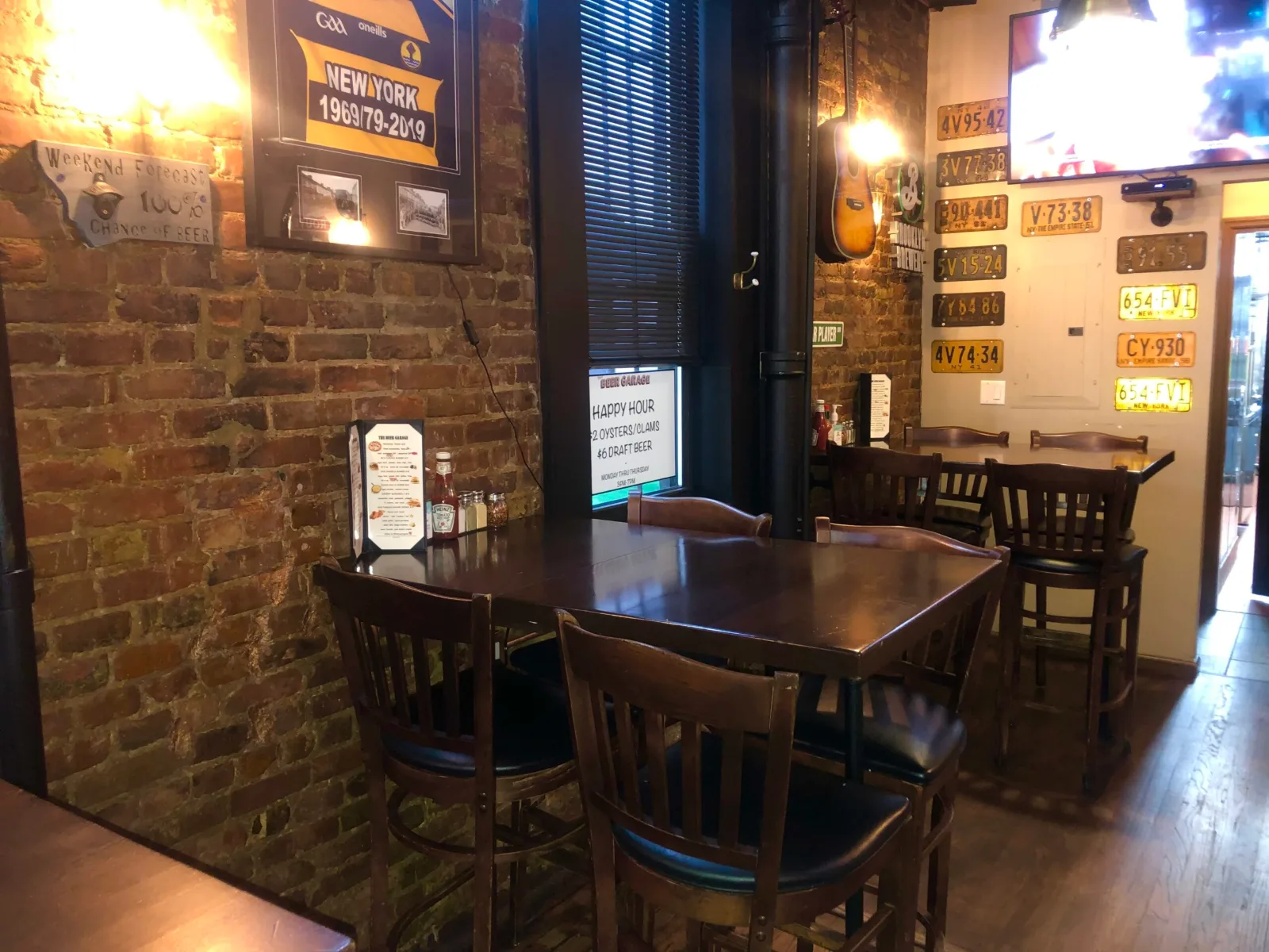 Brick walled dining area with wooden tables and menu boards at The Beer Garage, one place to watch UFC in Manhattan