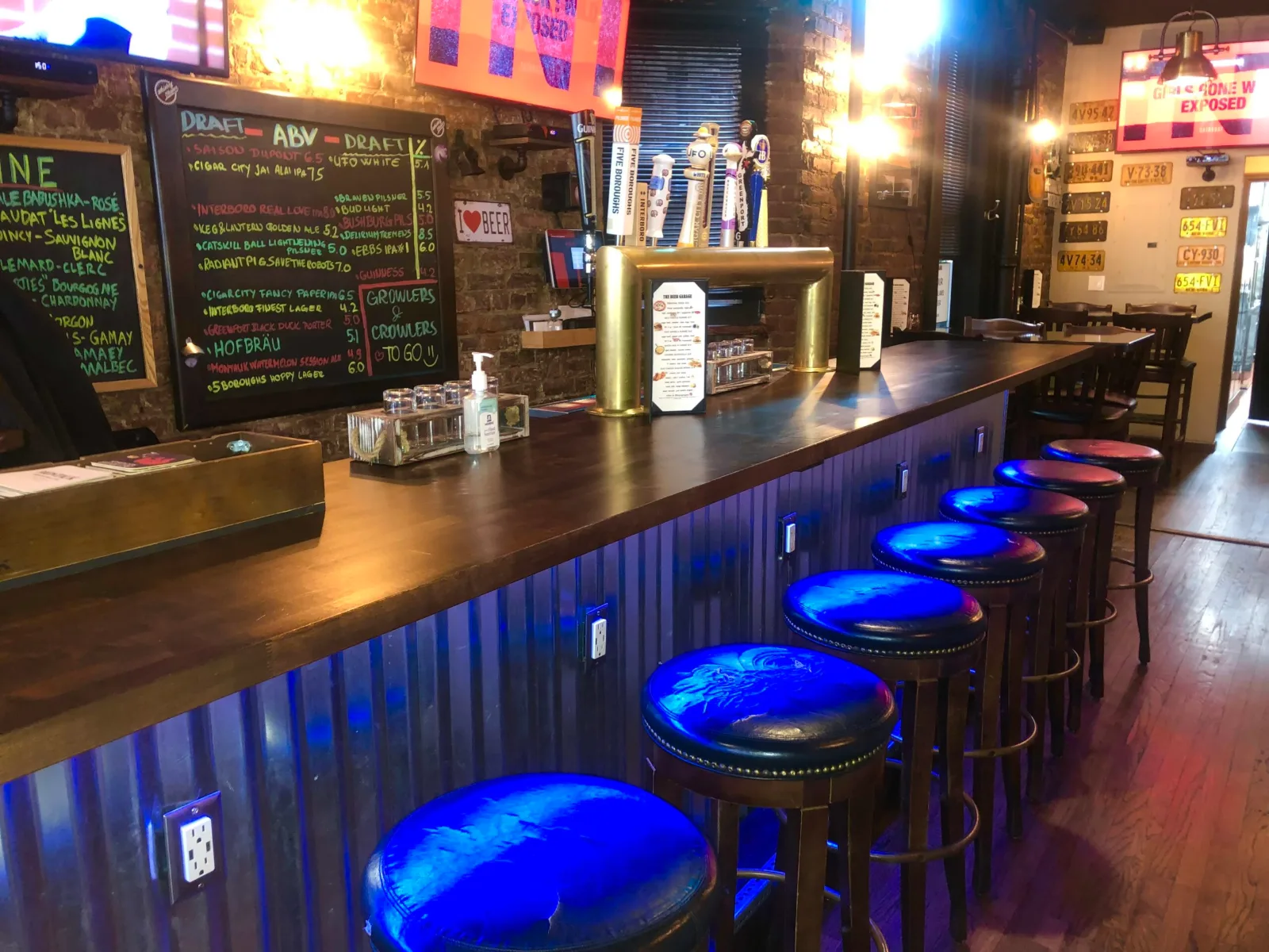 The bar counter at The Beer Garage in the West Village, a starting point for a date night bar in Manhattan, with blue-topped stools and chalkboard drink lists