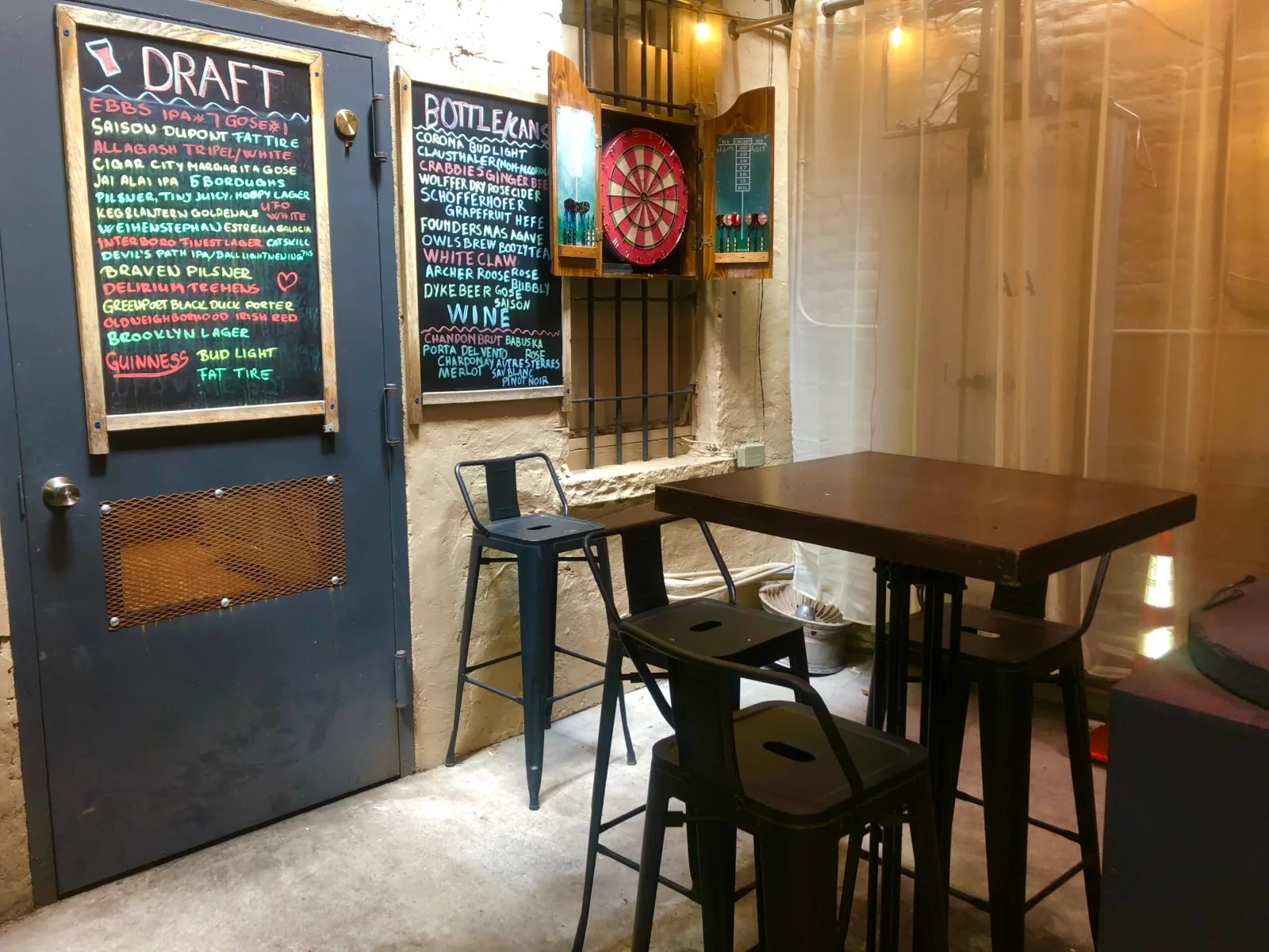 Chalkboard drink boards, a dartboard and high-top tables inside The Beer Garage West Village, one place to watch NHL hockey in Manhattan